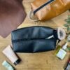 Trousse en cuir noir ouverte avec contenu — atelier maroquinerie Toulouse Trousse de toilette en cuir noir ouverte avec produits cosmétiques, réalisée lors d'un atelier créatif cuir à Tournefeuille