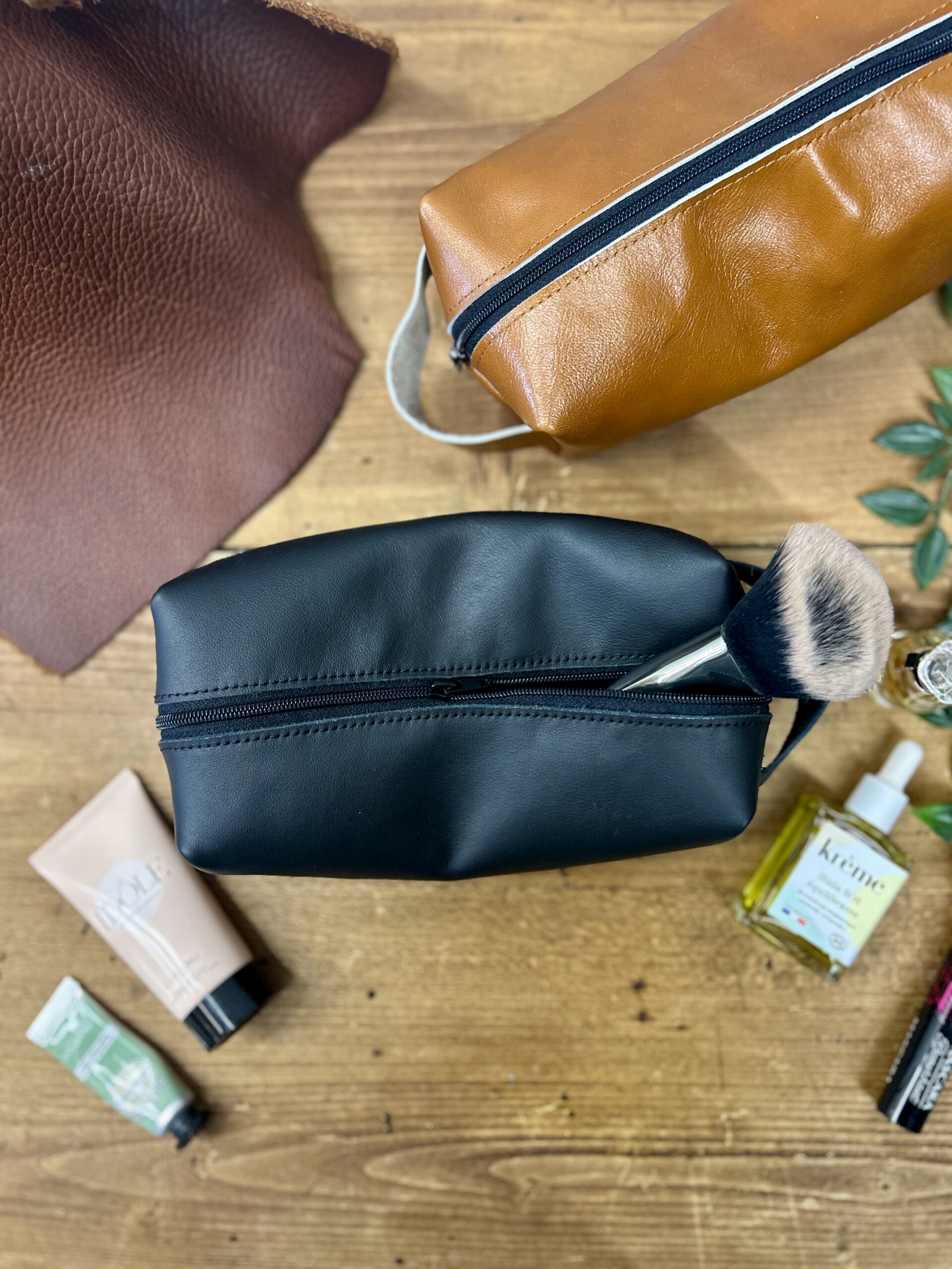 Trousse en cuir noir ouverte avec contenu — atelier maroquinerie Toulouse Trousse de toilette en cuir noir ouverte avec produits cosmétiques, réalisée lors d'un atelier créatif cuir à Tournefeuille