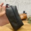 Trousse en cuir noir artisanale tenue en main — atelier Toulouse Trousse de toilette en cuir noir réalisée à la main lors d'un atelier créatif cuir à Tournefeuille près de Toulouse
