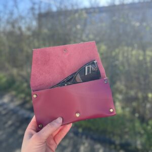 Étui à lunettes en cuir bordeaux ouvert avec une paire de lunettes de soleil, réalisé lors d'un atelier maroquinerie à Tournefeuille