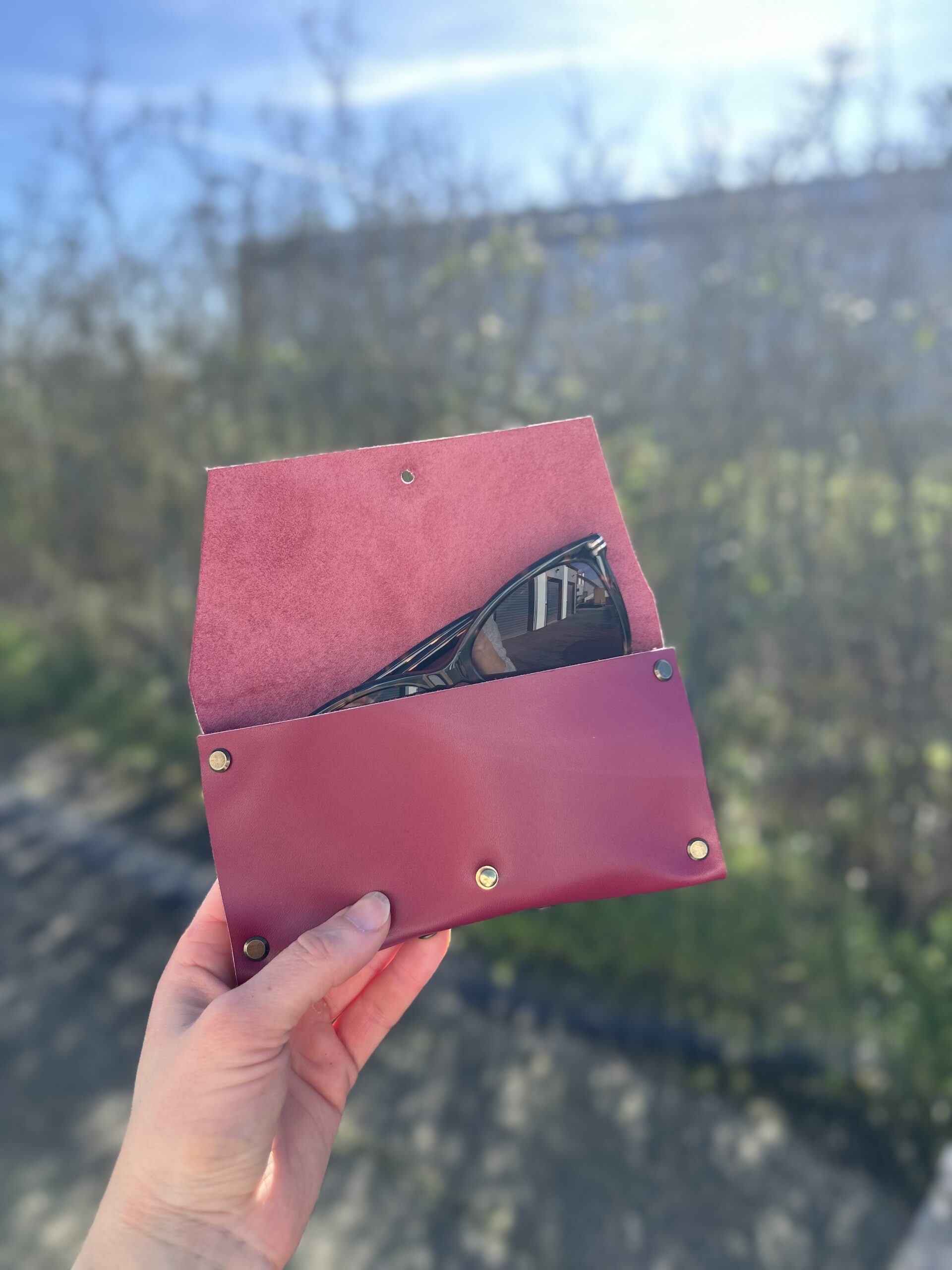 atelier-etui-lunettes-cuir-bordeaux-ouvert-toulouse Étui à lunettes en cuir bordeaux ouvert avec une paire de lunettes de soleil, réalisé lors d'un atelier maroquinerie à Tournefeuille